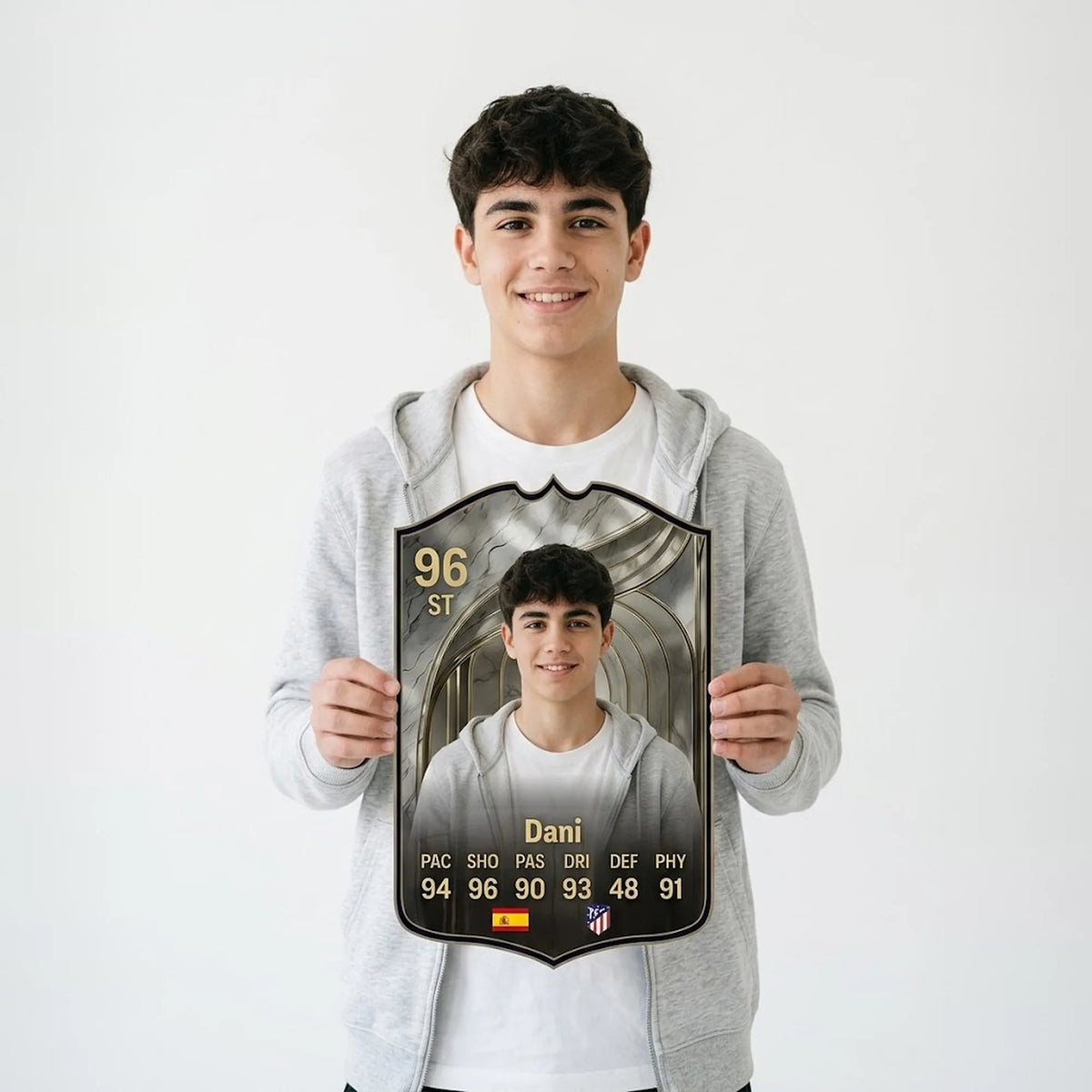 Chico con sudadera gris sosteniendo su carta de FIFA FC 26 Icon Prime personalizada — CardsGoat